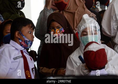 200826 -- JAKARTA, 26. Aug. 2020 -- Grundschüler beobachten einen Gesundheitsbeamten, der Zähne für einen ihrer Altersgenossen überprüft, bevor er einen Masern-Röteln-MR-Impfstoff während des COVID-19-Ausbruchs in Jakarta, Indonesien, am 26. Aug. 2020 verabreicht. Masern-Röteln-MRT-Impfstoffe werden Jugendlichen als Teil des Programms der indonesischen Regierung verabreicht, um Schulkindern eine angemessene Immunisierung anzubieten. INDONESIEN-JAKARTA-MASERN-RÖTELN-IMMUNISIERUNG AGUNGXKUNCAHYAXB. PUBLICATIONxNOTxINxCHN Stockfoto