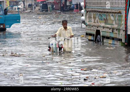 200827 -- PEKING, 27. August 2020 -- Ein Mann schiebt sein Motorrad am 26. August 2020 durch das Hochwasser in der südpakistanischen Hafenstadt Karachi. Neue heftige Regenfälle und Sturzfluten haben in Teilen Pakistans verheerende Folgen gehabt, mehrere Menschen getötet und Hunderte von Menschen vertrieben und viele Häuser beschädigt, berichteten lokale Medien am Mittwoch. STR/Xinhua XINHUA FOTOS DES TAGES Stringer PUBLICATIONxNOTxINxCHN Stockfoto