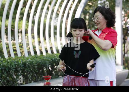 200828 -- PEKING, 28. August 2020 -- Mei Yongpei R bindet Enkelin Dong Yutong am Wukesong Diabolo Kulturplatz in Peking, Hauptstadt von China, 11. August 2020. Dong Shulin, 66, lebt mit seiner Frau Mei Yongpei und seiner 9-jährigen Enkelin Dong Yutong in Peking. Dong Shulin begann 2003 mit dem Diabolo-Spiel und nun spielt die ganze Familie gerne dieses traditionelle Volksspiel, bei dem man eine Spinnspitze werfen und fangen kann, indem man eine an zwei Stäben befestigte Schnur bewegt. In Dong Shulins Haus wurden über 70 Diabolos aufgestellt. Einige der Diabolos wurden gekauft, andere waren zu Hause Stockfoto