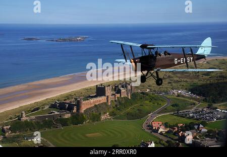 Die Tiger Moth aus dem Zweiten Weltkrieg führt über Bamburgh Castle in Northumberland in den Himmel. Die DH82A Tiger Moth wurde 1940 gebaut und gehört Darren Davis und Dave Burns von Tiger Flights, einem unabhängigen Unternehmen mit Sitz auf dem Eshott Airfield. Je nach Wetterlage wird G-EMSY das ganze Jahr über fliegen, was Luftfahrtfans das unvergleichliche Erlebnis des Cockpitflugs mit offenem Cockpit und einen einzigartigen Blick auf die Landschaft von Northumberland und ikonische Wahrzeichen bietet. Bilddatum: Dienstag, 5. September 2023. Stockfoto