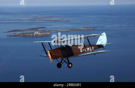 Die Tiger Moth aus dem Zweiten Weltkrieg bringt Sie über die Farne-Inseln in den Himmel. Die DH82A Tiger Moth wurde 1940 gebaut und gehört Darren Davis und Dave Burns von Tiger Flights, einem unabhängigen Unternehmen mit Sitz auf dem Eshott Airfield. Je nach Wetterlage wird G-EMSY das ganze Jahr über fliegen, was Luftfahrtfans das unvergleichliche Erlebnis des Cockpitflugs mit offenem Cockpit und einen einzigartigen Blick auf die Landschaft von Northumberland und ikonische Wahrzeichen bietet. Bilddatum: Dienstag, 5. September 2023. Stockfoto