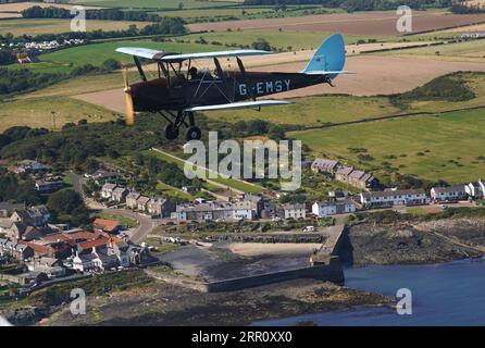 Die Tiger Moth aus dem Zweiten Weltkrieg bringt Sie in den Himmel über Craster in Northumberland. Die DH82A Tiger Moth wurde 1940 gebaut und gehört Darren Davis und Dave Burns von Tiger Flights, einem unabhängigen Unternehmen mit Sitz auf dem Eshott Airfield. Je nach Wetterlage wird G-EMSY das ganze Jahr über fliegen, was Luftfahrtfans das unvergleichliche Erlebnis des Cockpitflugs mit offenem Cockpit und einen einzigartigen Blick auf die Landschaft von Northumberland und ikonische Wahrzeichen bietet. Bilddatum: Dienstag, 5. September 2023. Stockfoto