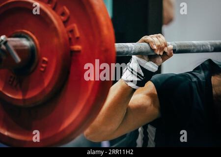 Nahaufnahme der Langhantel mit roten Platten und des weiblichen Powerlifters im Squat Stockfoto