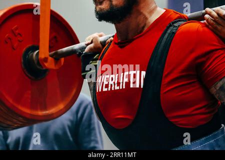 Nahaufnahme rote Platten Langhantel und männlicher Powerlifter Vorbereitung für Squat Powerlifting Stockfoto