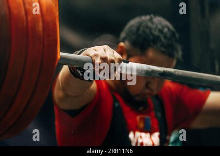 Nahaufnahme der Hände an der Langhantelstange, Vorbereitung auf das Powerlifting in der Hocke Stockfoto