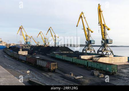 Kohleterminal Vyborg. Kräne und Eisenbahnwaggons befinden sich am Ufer neben Kohlestapeln, die auf Schiffe geladen werden können Stockfoto