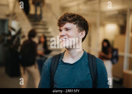 Glücklicher junger männlicher Student, der an der Universität steht Stockfoto
