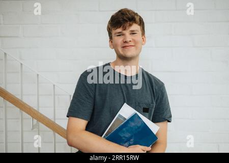 Porträt eines lächelnden männlichen Studenten, der Bücher in der Universität hält Stockfoto