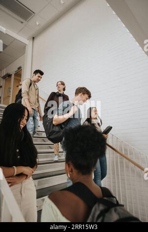 Glückliche männliche und weibliche multirassische Studenten auf Treppen in der Universität Stockfoto