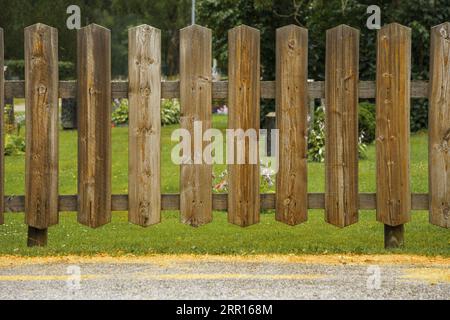 Holzzaun um einen Friedhof im Sommer. Stockfoto