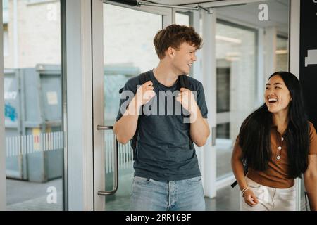 Fröhliche männliche und weibliche Studenten, die an der Universität ins Klassenzimmer gehen Stockfoto