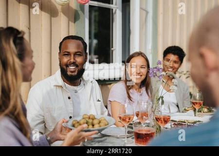 Eine Frau serviere Kinderkartoffeln an männliche und weibliche Freunde während der Dinnerparty im Café Stockfoto