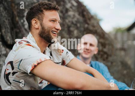 Glücklicher junger Mann mit Bart, der mit einem Freund sitzt Stockfoto