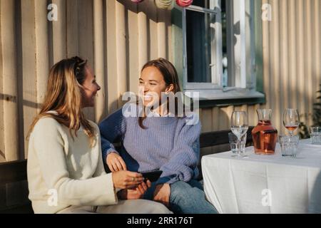 Glückliche junge Frauen, die während einer Dinnerparty im Café miteinander reden Stockfoto