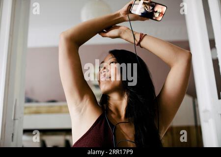 Glückliche junge Frau, die zu Hause Musik über Kopfhörer genießt Stockfoto