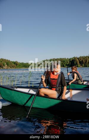 Mädchen schaut weg, während sie im Kajak auf dem See im Sommercamp sitzt Stockfoto