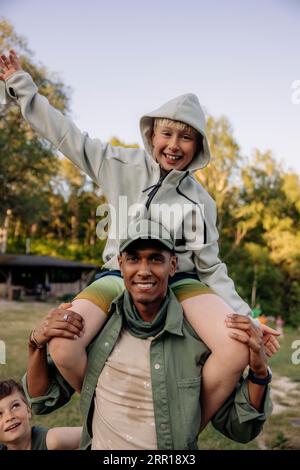 Porträt eines männlichen Betreuers, der einen fröhlichen Jungen auf den Schultern trägt, während er auf dem Spielplatz spielt Stockfoto