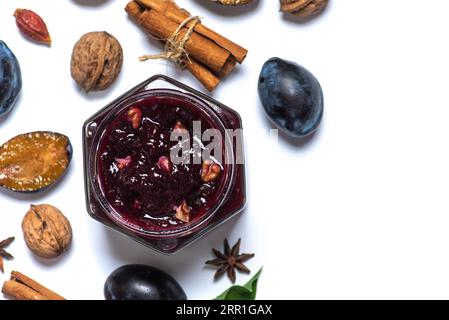 Hausgemachte Pflaumenmarmelade mit Zimt und Walnüssen, in einem Glas auf weißem Hintergrund Stockfoto