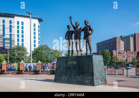 Die Skulptur United Trinity vor dem Old Trafford Stadion von Manchester United in Manchester, Großbritannien Stockfoto