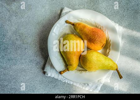 Blick von oben auf die weiße Marmorplatte mit frischen, saftigen Birnen auf einem Betontisch Stockfoto