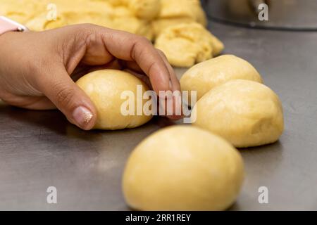 Ernten Sie anonymen schwarzen Bäcker, der rohen runden Brotteig aus einem Mehlstückchen auf einem Metalltisch in einer modernen Bäckerei herstellt Stockfoto