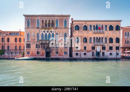 Fassaden verwitterter Gebäude mit Fenstern auf der Straße der Stadt Venedig in der Nähe des Kanalwassers bei Tageslicht Stockfoto