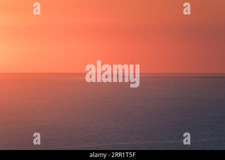 Atemberaubender Blick auf das Leuchtfeuer im Hintergrund der orangen Sonne im Sonnenuntergang über dem Meer in Marokko Stockfoto