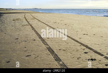 Spuren von einem Strandkiten-Buggy auf dem Sand mit Blick auf den Hafen von Dunkerque, Frankreich Stockfoto