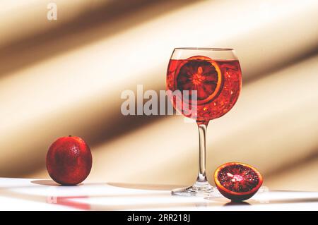 Rosso Tonic Summer Cocktail Drink mit rotem Wermut, Tonic, roter Orange und Eis im Weinglas. Beigefarbener Hintergrund, Minimalismus Stockfoto