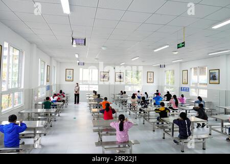 200929 -- SHIZHU, 29. September 2020 -- Schüler essen im Speisesaal der Grundschule der Gemeinde Zhongyi im autonomen Kreis Shizhu Tujia, südwestchinesische Gemeinde Chongqing, 8. Mai 2020. Zhongyi Township in Chongqing hatte eine hohe Armutsquote aufgrund schlechter Bodenqualität und unbequemer Transporte in einem bergigen Gelände. Vor 2018 gingen mehr als 60 Prozent der Arbeitskräfte im Dorf Huaxi in andere Städte, um ihren Lebensunterhalt zu verdienen, was fast 60 Prozent des Ackerlandes unbewirtschaftet ließ. Doch die Bemühungen zur Armutsbekämpfung begannen 2018, Huaxi zu verändern. Um V zu helfen Stockfoto