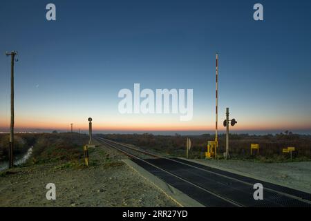 Sonnenaufgangsbild eines Bahnübergangs in Küstennähe Stockfoto