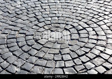 Hintergrund der alten Pflastersteinpflasternaht. Steinpflaster in der Perspektive, Textur der Kopfsteinpflasterstraße, grauer Kopfsteinpflasterstraßenhintergrund. Stockfoto