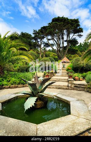 Mediterraner Garten mit Brunnen, Agave-Skulptur, subtropischer Garten aus dem 19. Jahrhundert, Tresco Abbey Garden, Scilly-Inseln, Cornwall, England, Vereint Stockfoto