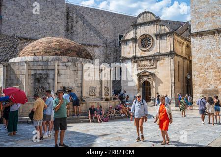 Touristen versammelten sich am Big Onofrio's Fountain mit der Kirche St. Erlösung darüber hinaus in der alten ummauerten Stadt Dubrovnik an der dalmatinischen Küste Kroatiens Stockfoto