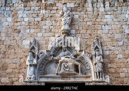 Pieta-Skulptur über dem Seiteneingang zum Franziskanerkloster auf Stradun (Placa) in der alten ummauerten Stadt Dubrovnik an der dalmatinischen Küste von Kroatien Stockfoto