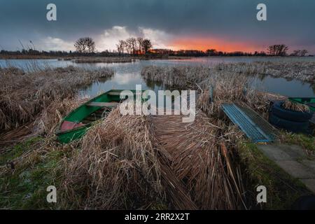 Im Schilf am Ufer des Sees verankertes Boot, Blick bei Sonnenuntergang, Ostpolen Stockfoto