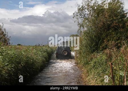 Erhöhter Wasserstand auf der Weserinsel Strohauser Plate, Auto fährt auf einer überfluteten Betonstraße, Strohauser Plate, Wesermarsch, unten Stockfoto