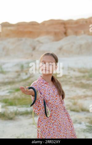 Ein Teenager spielt mit einer Schlange und hält sie in den Händen. Kinder und Schlange die Wildnis. Stockfoto