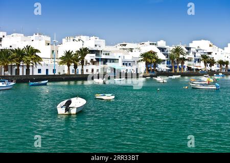 Weiße Gebäude vor blauem Himmel und kleine fischerboote an der laguna Charco de San Gines an einem sonnigen Wintertag, Arrecife, Hauptstadt von Lanzarote, Spanien. Stockfoto