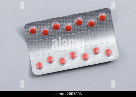 Verpackung roter Arzneipillen auf grauem Hintergrund. Globales Gesundheitskonzept. Antibiotikaresistenz. Antimikrobielle Kapseltabletten. Stockfoto