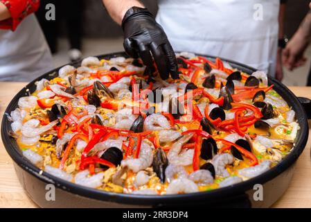 Die Person kocht Paella mit Meeresfrüchten in einer Küche des Meisterkurses, aus nächster Nähe rohe ungekochte Produkte Stockfoto