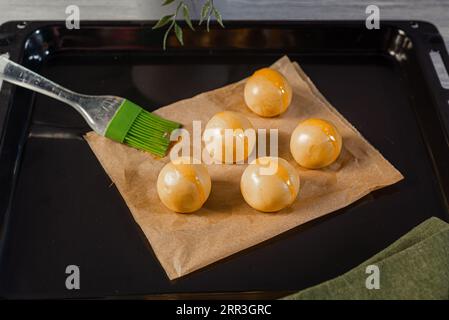 Teigkugeln auf mit Eigelb bestrichenem Backpapier Stockfoto