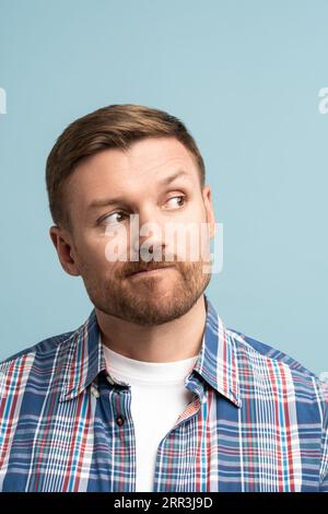 Nachdenklicher Mann mittleren Alters, der die Lippen in der oberen rechten Ecke trägt, trifft die Wahl, auf dem Kopierplatz. Stockfoto