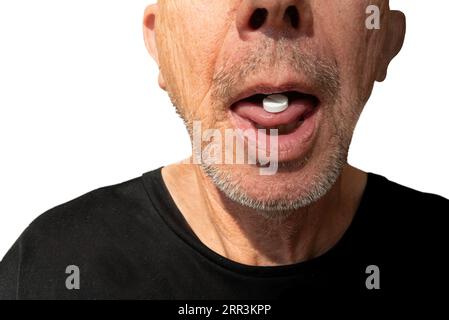 Der Mann nimmt Medikamente. Weiße Pille auf Zunge bei reifem Mann mit Stoppeln. Nahaufnahme des Bildes isoliert auf weiß. Stockfoto