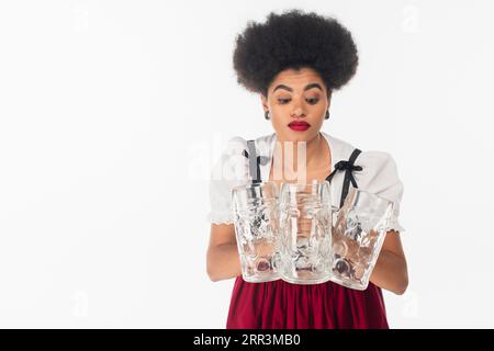 Entmutigte afroamerikanische bayerische Kellnerin im oktoberfest-Outfit mit leeren Bierbechern auf weiß Stockfoto