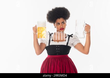 Unzufriedene afroamerikanische oktoberfest-Kellnerin im Dirndl mit Blick auf leeren Bierkrug auf weiß Stockfoto