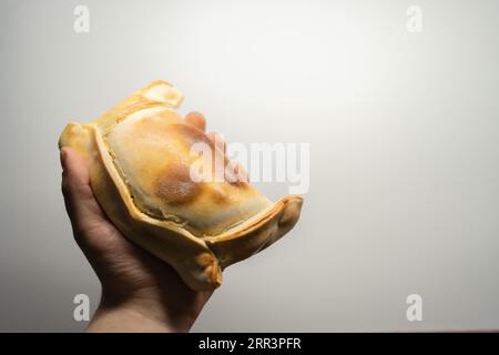 Die Hand des Mannes hält eine chilenische Empanada de Pino auf weißem Hintergrund Stockfoto