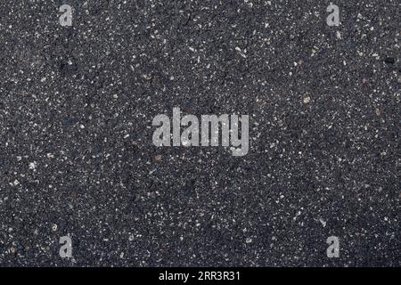 Oberfläche Grunge rauer Asphalt, dunkle, körnige Straße Nahaufnahme, schwarzer Texturhintergrund mit kleinen Felsen, Draufsicht Stockfoto