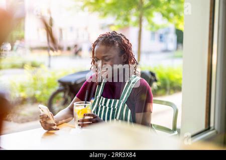 Porträt einer schwarzen nichtbinären Person, die in einem Café im Freien sitzt Stockfoto