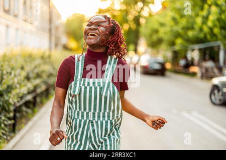 Fröhliche nicht-binäre Person, die auf der Straße in der Stadt tanzt Stockfoto